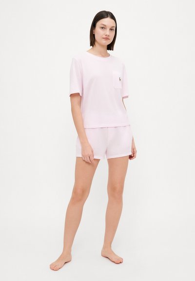 Light pink cotton t-shirt with short sleeves and a pocket, paired with matching shorts. Simple design, soft texture, and no patterns.