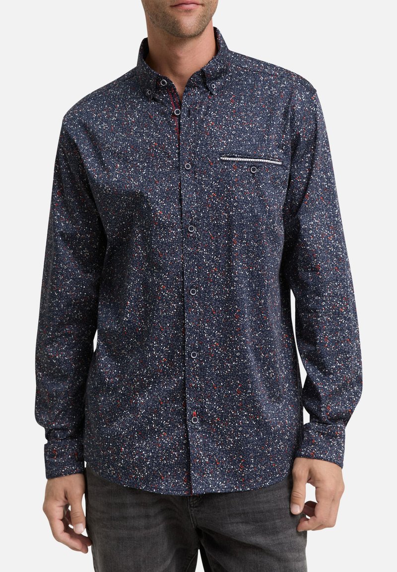 Chemise à manches longues, boutonnée, navy avec un motif tacheté en blanc et rouge. Dotée d'une poche poitrine avec des rayures contrastantes. Tissu doux.