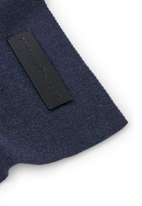 Granatowy materiał o miękkiej, dziewiarskiej teksturze z prostokątną czarną metką wytłoczoną z napisem "ADOLFO DOMINGUEZ".