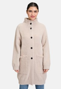 Beżowy płaszcz długi z wełny z wysokim kołnierzem, z czarnymi guzikami, dwoma przednimi kieszeniami i miękkim, teksturowanym wykończeniem.