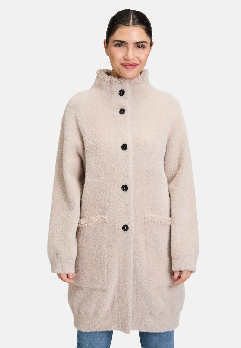 Beżowy płaszcz długi z wełny z wysokim kołnierzem, z czarnymi guzikami, dwoma przednimi kieszeniami i miękkim, teksturowanym wykończeniem.