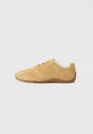 Tan suede sneaker with a rounded toe, textured upper featuring stitching details, a padded collar, and a rubber outsole for traction.