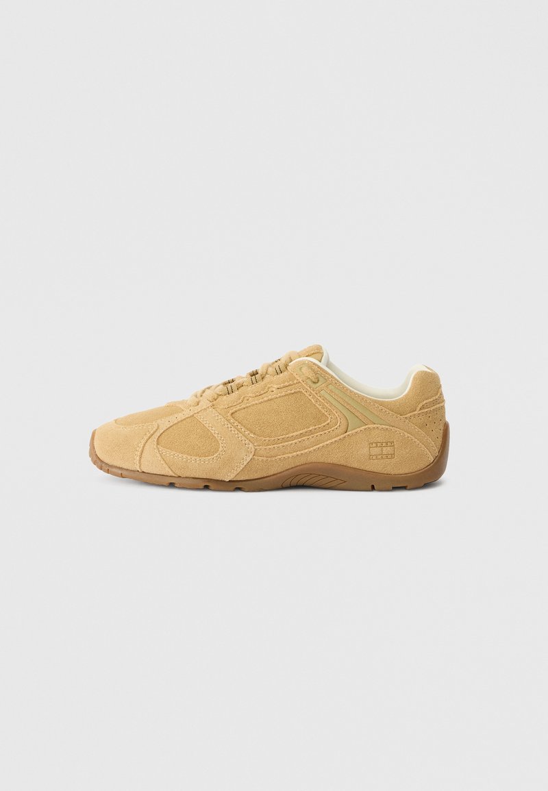 Tan suede sneaker with a rounded toe, textured upper featuring stitching details, a padded collar, and a rubber outsole for traction.