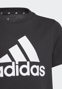 T-shirt nera in cotone con un grande logo Adidas bianco. Design classico con collo rotondo e maniche corte, dalla texture liscia.