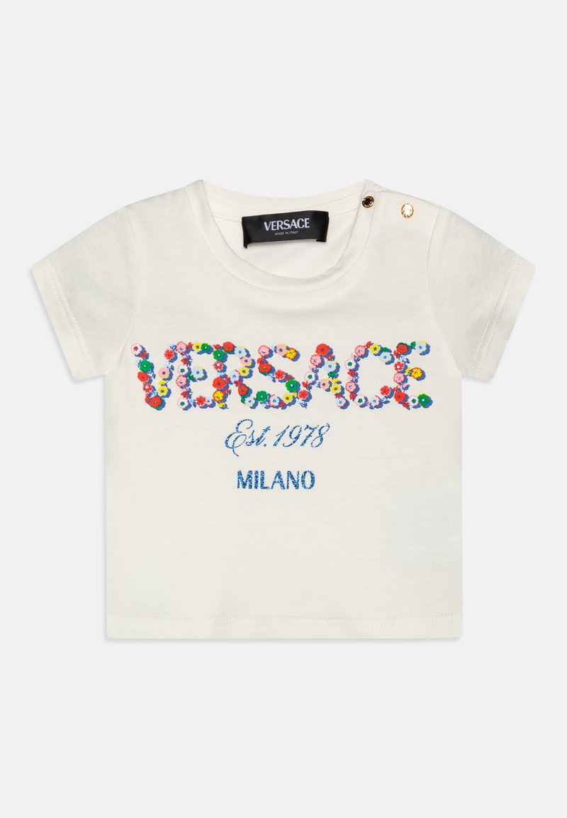 Bela bombažna majica s pisanimi cvetličnimi vezeninami "VERSACE," "Est. 1978," in "MILANO," ter z zlatim gumbom na rami.