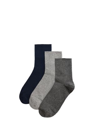 Tres calcetines altos lisos en azul oscuro, gris claro y gris oscuro, dispuestos uno al lado del otro sobre un fondo blanco.