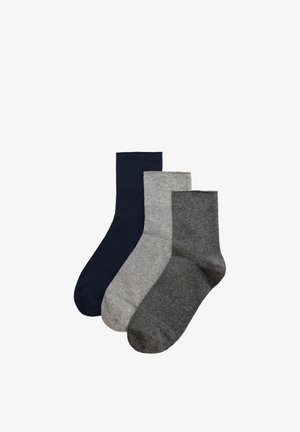 Tres calcetines altos lisos en azul oscuro, gris claro y gris oscuro, dispuestos uno al lado del otro sobre un fondo blanco.