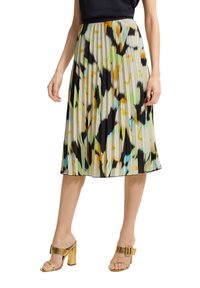 Falda midi plisada de un vibrante patrón abstracto en verdes, negros y naranjas, hecha de una tela ligera. Combinada con tacones de bloque dorados.