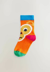 Bunte Kindersocke mit orangefarbenem Grund, blauen Rippbündchen, grüner Spitze und einem verspielten Tiergesicht-Design mit großen Augen und einem rosa Akzent.