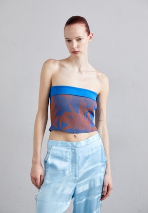 Strapless top in blue with a ribbed texture and contrasting orange floral pattern; paired with light blue satin wide-leg pants.