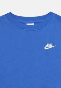 Blå bomullssvettegenser med rund hals, med en hvit Nike-logo brodert på brystet. Myk tekstur og jevn finish.