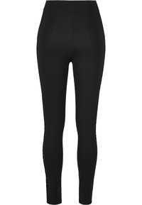 Svart leggings laget av elastisk stoff, med en glatt tekstur og gjennomsiktige mesh-paneldetaljer på sidene for ekstra detaljer.