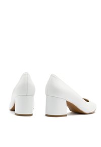 Białe skórzane buty na blokowym obcasie z zaokrąglonym czubkiem i wycięciami, o gładkiej fakturze i kontrastującej beżowej podeszwie.