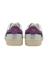 Zapatillas blancas con acentos de ante morado en el talón, paneles laterales en azul marino y suelas de goma beige. Presentan detalles de costura y un logo en el talón.