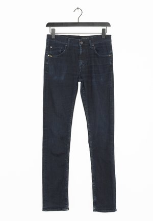 Ciemnoniebieskie jeansy slim fit wiszące na czarnym wieszaku na białym tle, ukazujące przednie kieszenie, guzik i zamek błyskawiczny.
