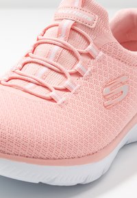 Světle růžová sportovní bota s síťovinovým svrškem, elastickými tkaničkami a bílou gumovou podrážkou. Na boku je jemné logo.