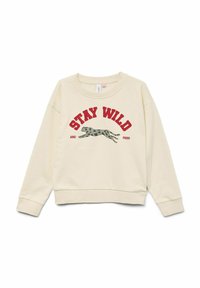 Krämfärgad sweatshirt med rund halsringning, ribbade ärmslut och en grafisk tryck av en hoppande leopard. Texten lyder "STAY WILD AND FREE" i rött.