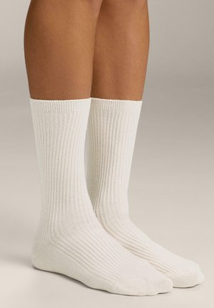Calzini bianchi a coste con una texture morbida, lunghezza a metà polpaccio, con un motivo uniforme e punta e tallone rinforzati.