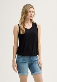 Sort ærmeløs top med tekstureret mønster, parret med lyseblå denim shorts med oprullede manchetter. Enkel, afslappet sommeroutfit.
