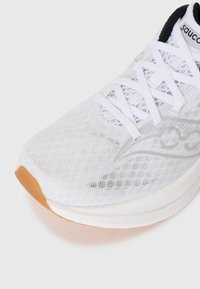 Hvide mesh sportssko med en blød sål, prydet med et sølvlogo, hvide snørebånd og en lys orange accent på ydersålen.