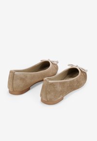 Bailarinas de ante en beige claro con una textura suave, punta redondeada y un lazo decorativo en la parte delantera. Suela plana de goma para mayor comodidad.