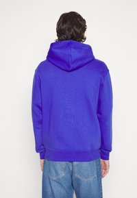 Sudadera con capucha en azul brillante. Cuenta con mangas largas, puños acanalados y un ajuste holgado. Tejido liso sin logotipos ni patrones visibles.