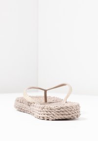 Béžové žabky s texturovanou tkanou podešví, tenkými popruhy a třpytivým akcentem na popruhu. Jednoduchý a minimalistický design.