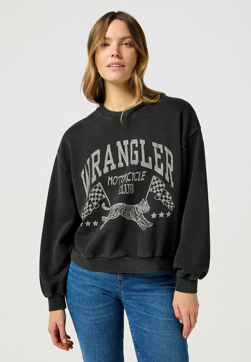 Czarny sweter z grafiką przedstawiającą tygrysa, szachownicowe flagi i napis "WRANGLER MOTORCYCLE CLUB". Dół oraz mankiety zakończone ściągaczem.