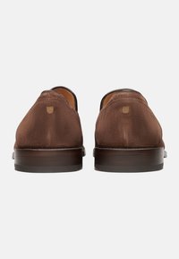 Mocassini in suede marrone con una finitura in pelle liscia e suola in legno. Presentano una punta arrotondata e un dettaglio di cucitura minimale sul retro.