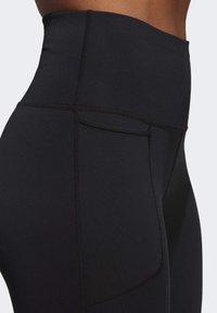 Sorte højtaljede leggings med en glat tekstur, der har en sidelomme og kontrasterende søm for ekstra detalje.