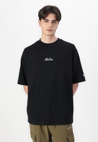 Black short-sleeve t-shirt made of cotton, featuring a white embroidered logo on the chest and a relaxed fit. Plain design, no patterns.