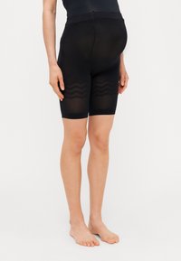 Calças de maternidade pretas com um cós elástico, apresentando uma textura suave e padrões em ondas nas coxas. Design até ao joelho.