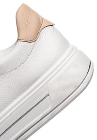Witte leren sneakerhiel met beige leren accent en een witte rubberen zool met textuur, afgebeeld tegen een witte achtergrond.