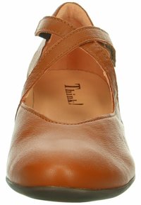 Scarpa in pelle marrone con punta arrotondata, caratterizzata da cinturini incrociati e un sottopiede in finta pelle. Suola piatta con una leggera texture.