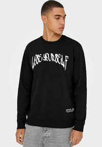 Felpa nera con il testo stilizzato bianco "LOOSE YOURSELF" sul petto e un piccolo dettaglio del logo all'orlo. Presenta un colletto e polsini a coste.