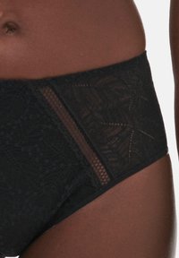 Schwarze hochgeschnittene Panties mit Spitzenüberzug, die ein florales Muster aufweisen und transparente Seiteneinsätze bieten, was eine kontrastierende Textur schafft.