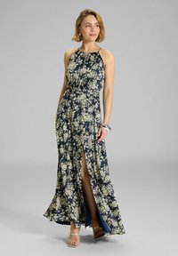 Navy sininen maksimekko, jossa on kaarrokeolkaimet, kerätty vartalo ja reiten yli ulottuva halkio. Kangas on sileä ja siinä on kermavärisiä kukkakuvioita.