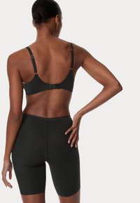Conjunto de sujetador y pantalones cortos negro hecho de tela suave. El sujetador tiene tirantes ajustables y un cierre de gancho; los pantalones cortos tienen un diseño sin costuras.