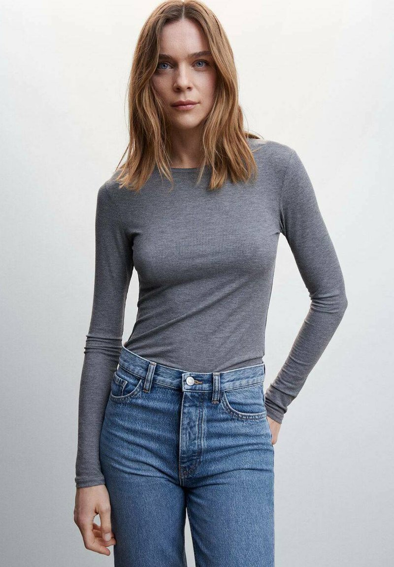 Un haut gris à manches longues en côtes associé à un jean bleu taille haute. Le tissu est doux, avec des manches ajustées et un col rond.