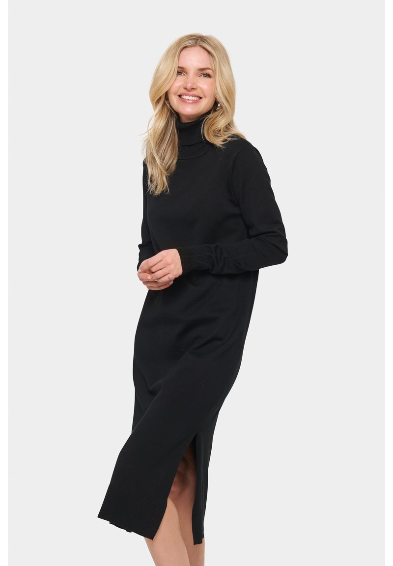 Černé pletené šaty s dlouhým rukávem a vysokým límcem, s bočními rozparky na spodním lemu a ribovanými manžetami, které zdůrazňují priléhavou siluetu.