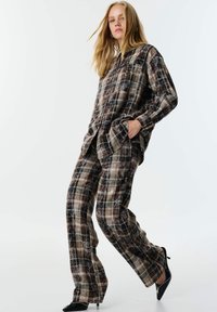 Braun karierte Loungewear-Set mit einem Hemd mit Knöpfen und weit geschnittenen Hosen, aus weichem Stoff mit subtiler Textur und Taschen.