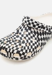 Black and white checkered clog made of lightweight material, featuring ventilation holes, a rounded toe, and a flexible strap for secure fit.