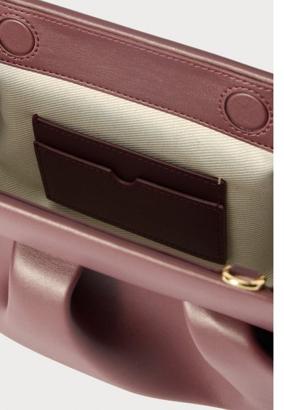 Ανοιχτό μωβ δερμάτινο κλάθ με κρεμ ύφασμα επένδυσης και εσωτερική τσέπη για κάρτες σε σκούρο χρώμα, που δείχνει μαγνητικά κλείστρα και λεπτομέρεια χρυσού δαχτυλιδιού.