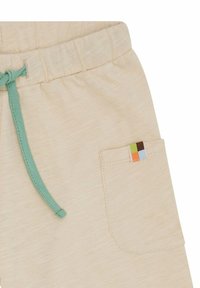 Helle beige Shorts mit strukturiertem Finish, ausgestattet mit einem elastischen Bund und einer mintgrünen Kordel sowie einem bunten aufgenähten Taschen-Detail.