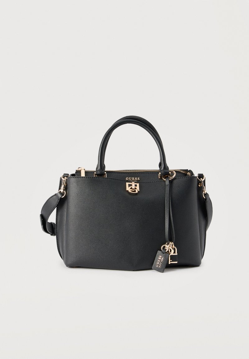 Μαύρη τσάντα Guess με διπλές λαβές, χρυσούς μεταλλικούς εξαρτήματα, κλείσιμο με φερμουάρ και μπρελόκ με λογότυπο που κρέμεται στο πλευρό.