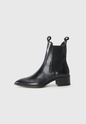 Mustat nahka nilkkurit, joissa on terävä kärki, elastiset sivupaneelit ja vetoketjut. Varustettu matalalla boksikorkeudella ja sileällä pinnalla.