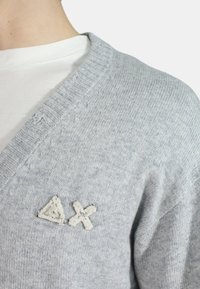 Cardigan grigio a maglia con scollo a V, dal tocco morbido, con triangoli bianchi ricamati e simboli X sul lato sinistro.
