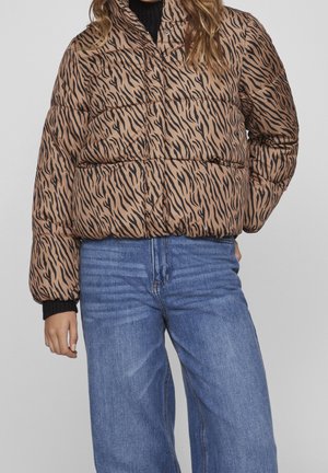 Prošívaná bunda s hnědo-černým tygřím pruhovaným vzorem, vysokým límcem a elastickými manžetami, spárovaná se světle modrými kalhotami s vysokým pasem.