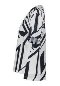 Camicia a maniche corte bianca con audaci motivi geometrici neri. Tessuto morbido, vestibilità rilassata e orlo arrotondato.