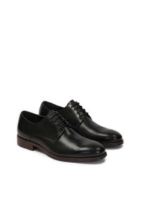 Pantofi de piele negrii cu o finisare netedă, vârful rotund și închidere cu șireturi. Prezintă o talpă din lemn maro pentru un contrast suplimentar.